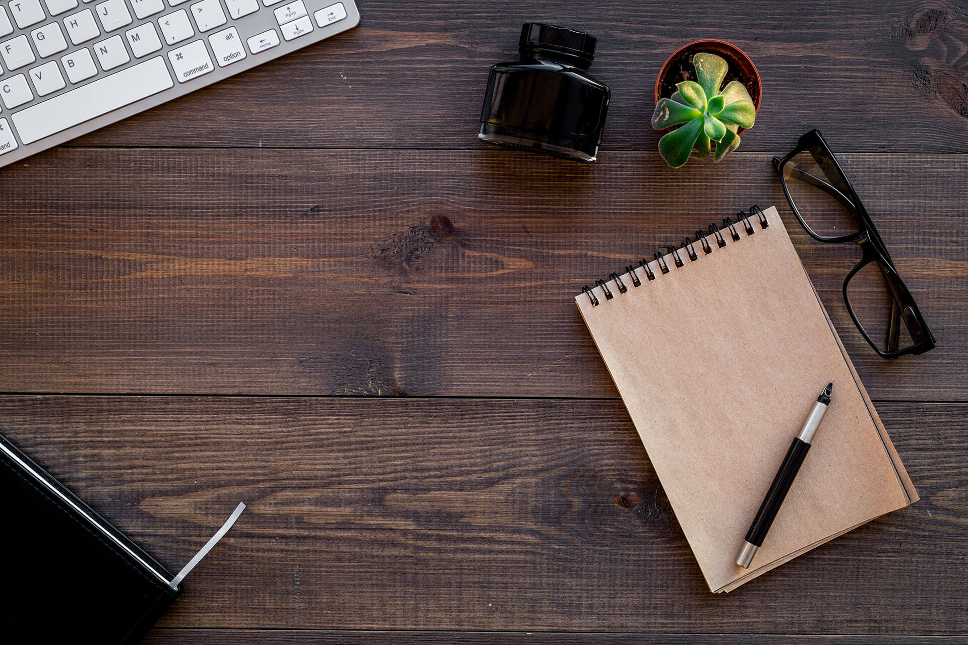 Picture of notebook, pen, eye glasses and computer keyboard